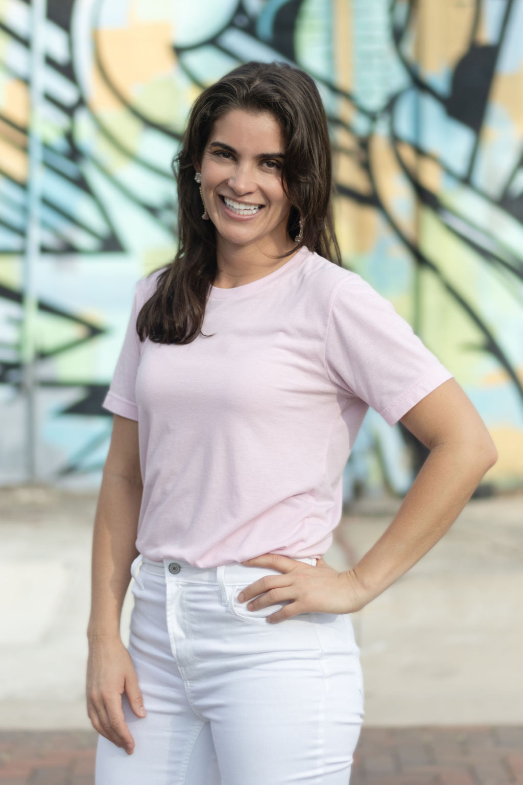 Woman in pink shirt standing in front of a mural